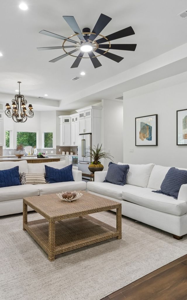 Open living room with a white sectional, navy pillows and a woven coffee table.